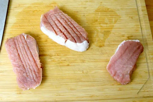 Pound the pork chops with the spine of the cleaver.