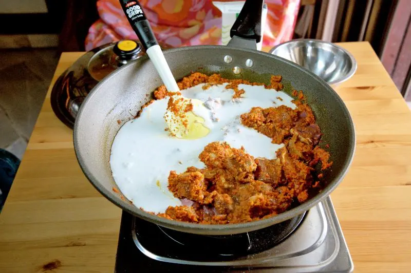 Add the coconut cream and some water to the curry paste in the wok.