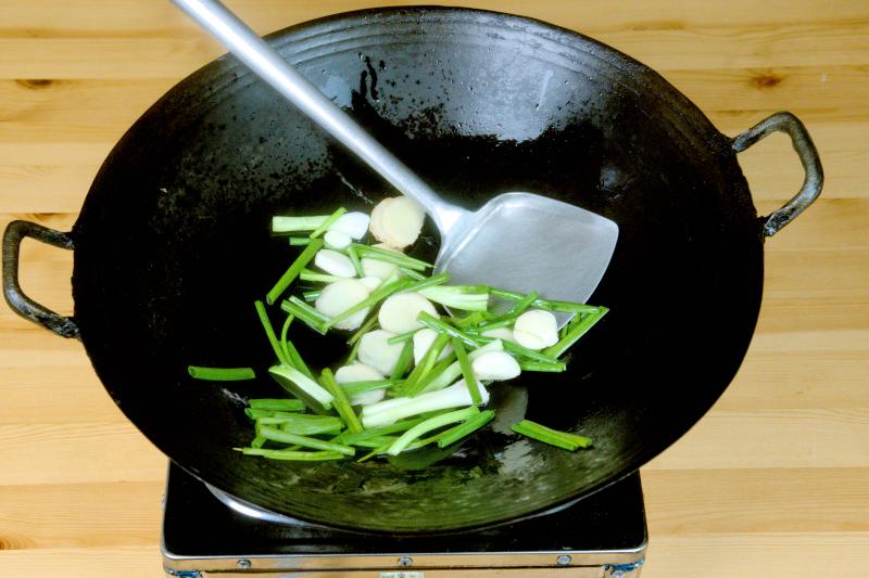 Saute the green onions, sliced ginger, and garlic cloves