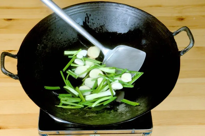 Saute the green onions, sliced ginger, and garlic cloves